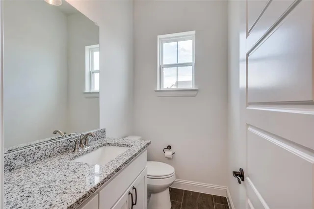 a bathroom with a granite countertop sink a toilet and a mirror