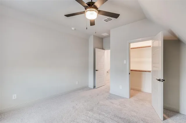 an empty room with closet and a chandelier fan