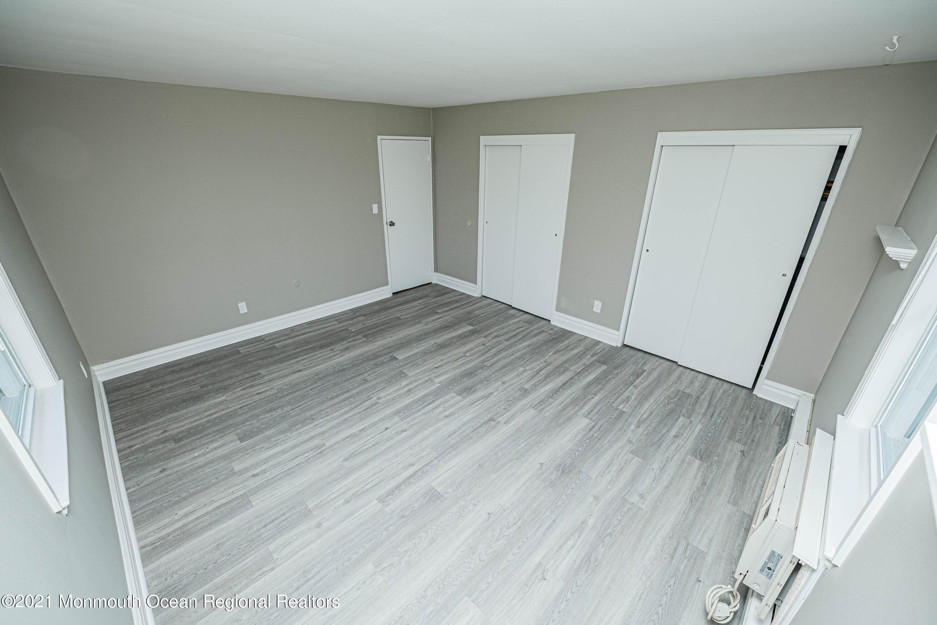 59 Stonehurst Boulevard, Unit B Freehold, NJ 07728 - Photo 18 of 25 a view of an empty room with wooden floor and a window