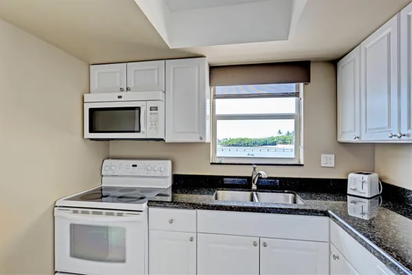 a kitchen with white cabinets and appliances