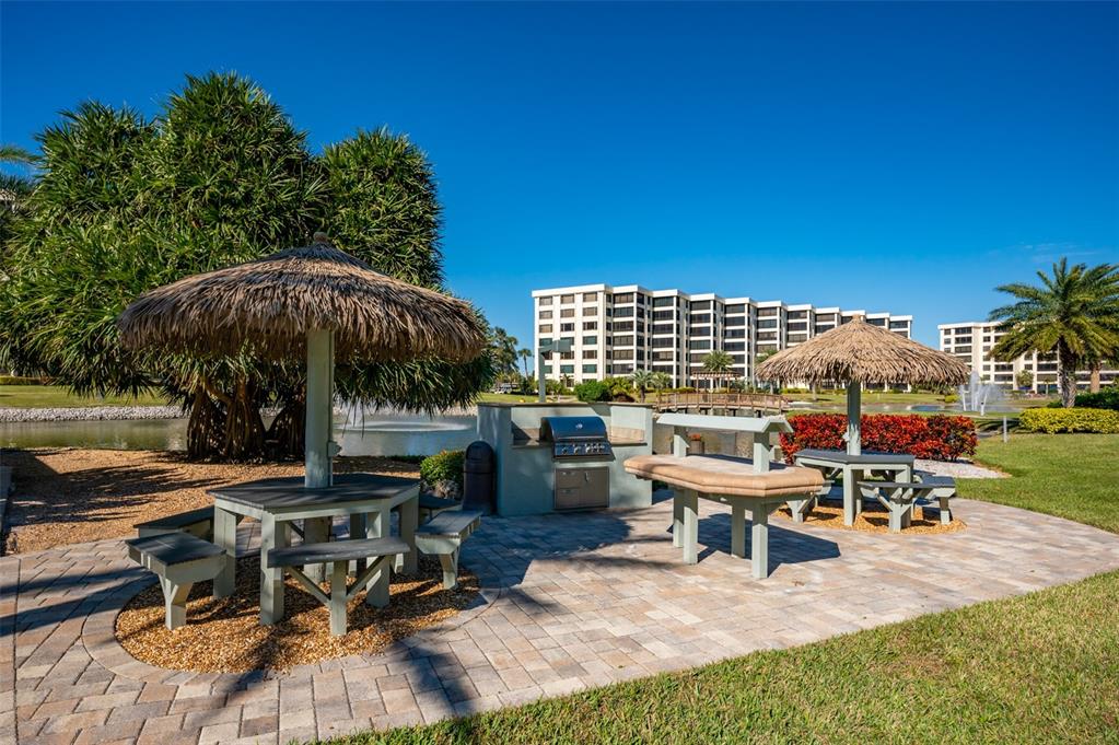 5780 Midnight Pass Road, Unit 210 Sarasota, FL 34242 - Photo 44 of 58 a view of a patio with table and chairs under an umbrella with a barbeque