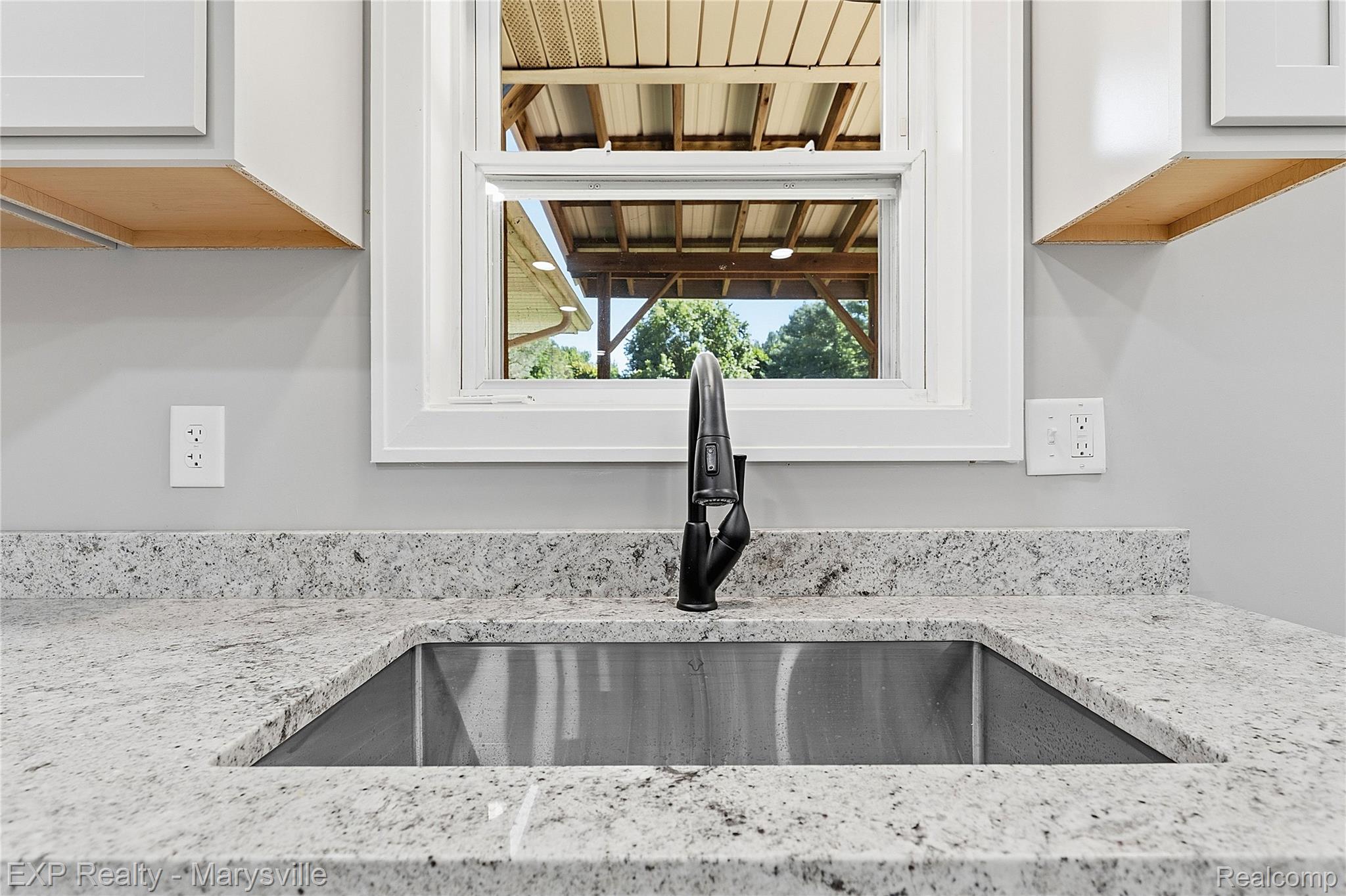 13739 Yale Road Yale, MI 48097 - Photo 12 of 50 Undermount stainless steel sink with a matte black faucet, set into a speckled countertop