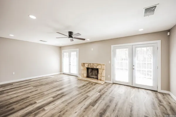 an empty room with wooden floor fireplace and windows
