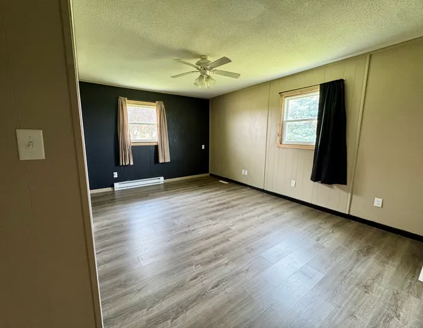 an empty room with wooden floor and windows