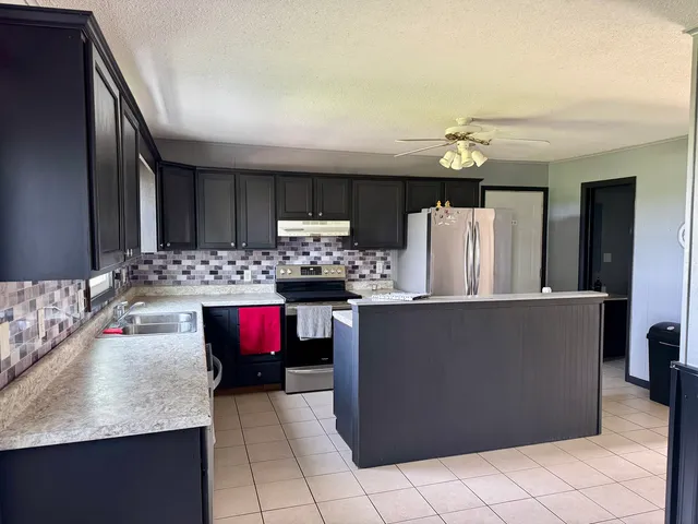 a kitchen with stainless steel appliances kitchen island granite countertop a refrigerator and a stove