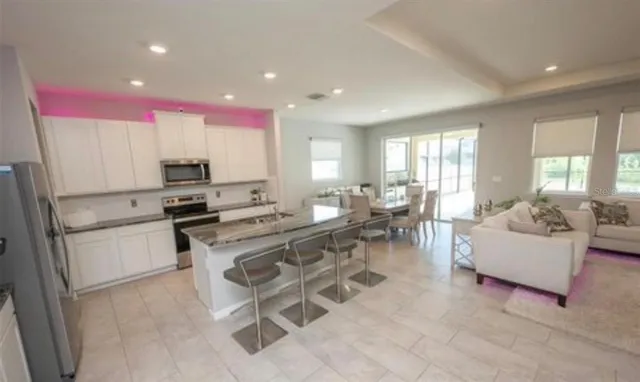 a living room with stainless steel appliances furniture a rug and a window