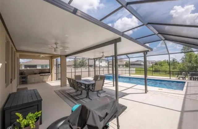a view of a dining room with furniture a chandelier and large windows