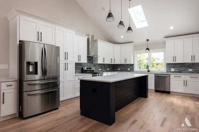 a kitchen with kitchen island granite countertop a refrigerator a sink dishwasher a stove and white cabinets with wooden floor