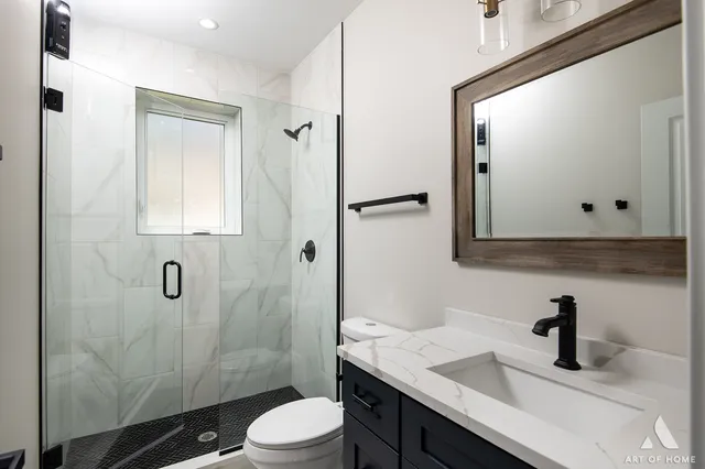 a bathroom with a granite countertop sink toilet a mirror and shower