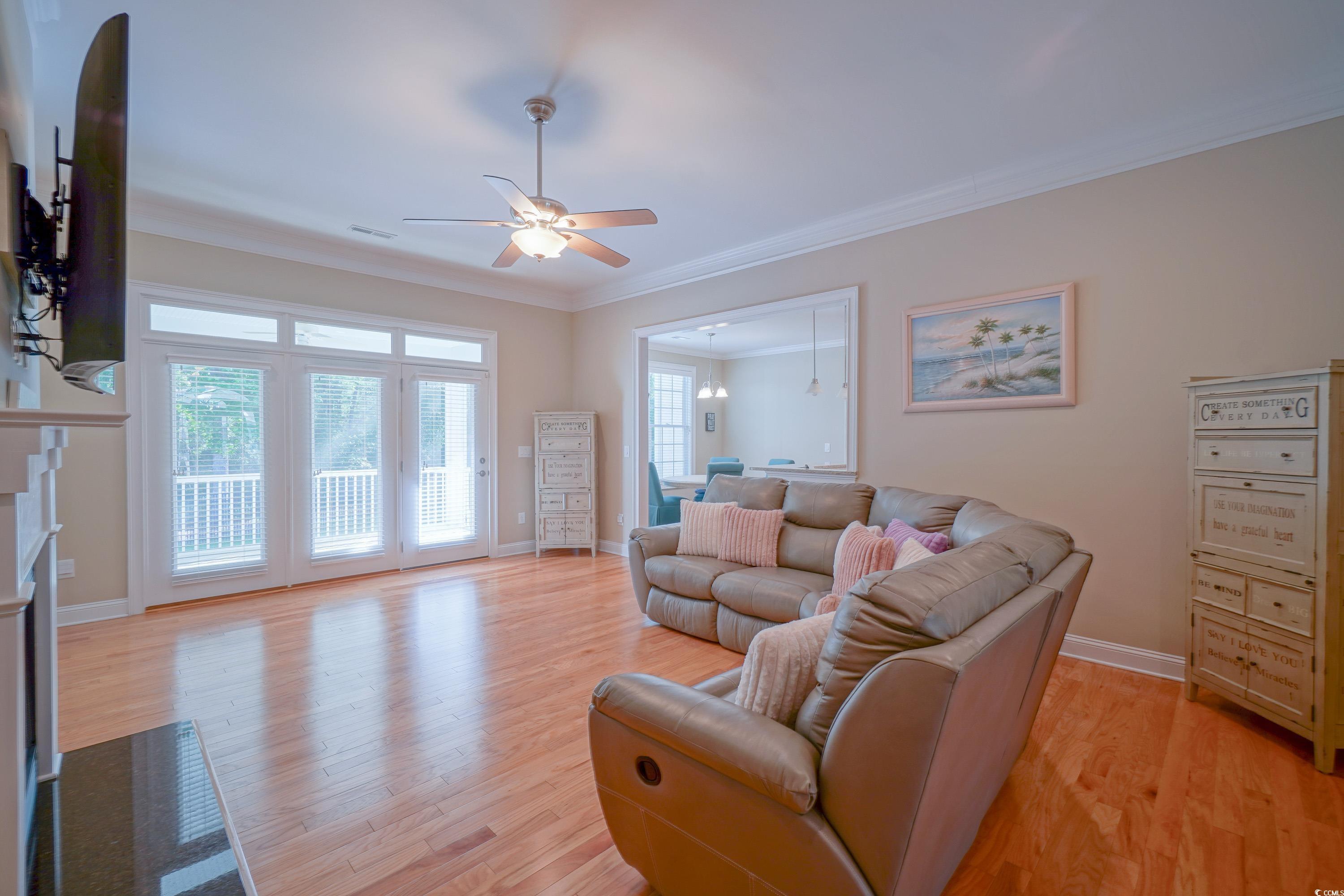 625 Whispering Pines Court Murrells Inlet, SC 29576 - Photo 6 of 36 Living room with crown molding, light wood-style floors, a ceiling fan, baseboards, and visible vents