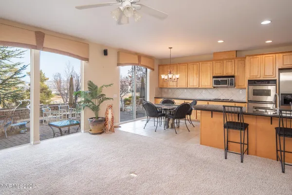 a kitchen with stainless steel appliances granite countertop a stove top oven a sink a dining table and chairs with the view of kitchen