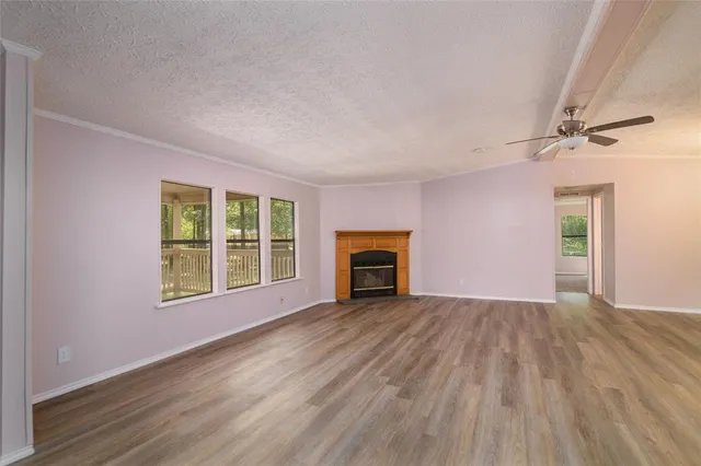 a view of an empty room with wooden floor fireplace and a window