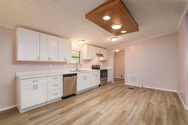 a open kitchen with white cabinets and wooden floor