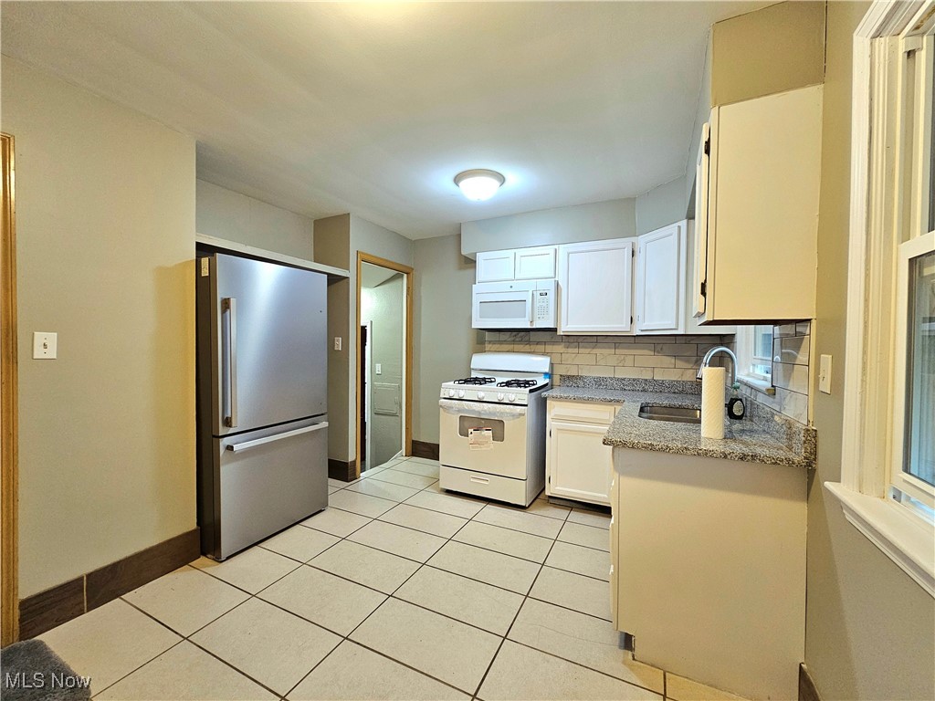 13514 Granger Road Cleveland, OH 44125 - Photo 5 of 23 Kitchen with white cabinetry, light tile patterned flooring, backsplash, white appliances, and sink