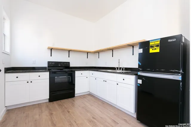 a kitchen with granite countertop a sink cabinets and stainless steel appliances
