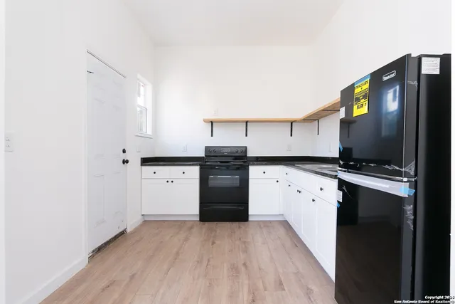 a kitchen with granite countertop a refrigerator stove and oven with wooden floor
