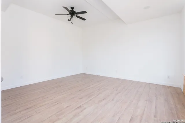 an empty room with wooden floor and a ceiling fan