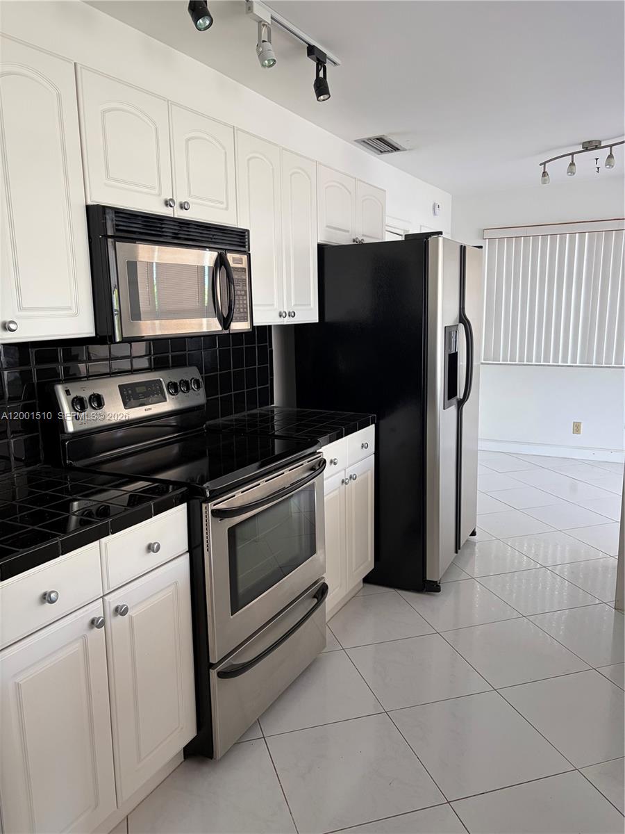 3205 Liberty Street Hollywood, FL 33021 - Photo 3 of 12 a kitchen with stainless steel appliances granite countertop a stove a refrigerator and a microwave