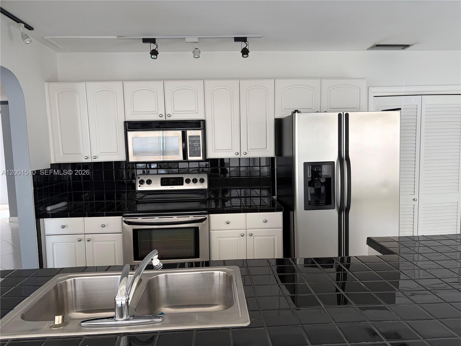 3205 Liberty Street Hollywood, FL 33021 - Photo 4 of 12 a kitchen with granite countertop a refrigerator and a stove top oven
