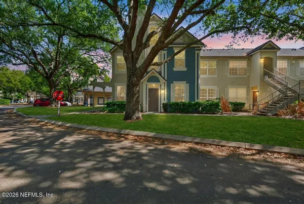 a view of a brick house with a big yard and large trees