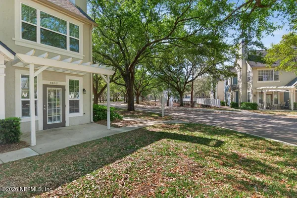 a view of a brick house with a big yard and large trees