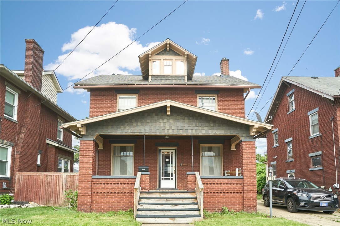 136 Smith Avenue Northwest Canton, OH 44708 - Photo 1 of 19 Brick residence featuring a covered front porch with shingle siding details, prominent brick chimney, and a dormer window