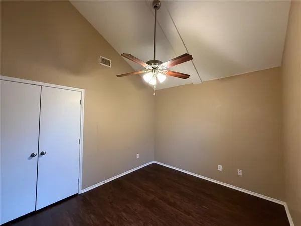 an empty room with a ceiling fan and wooden floor