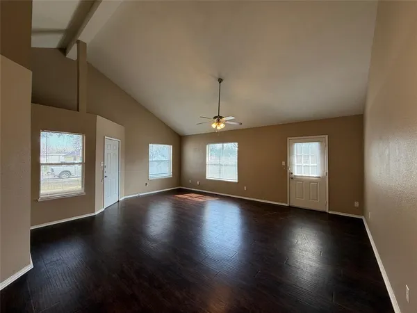 an empty room with wooden floor and windows