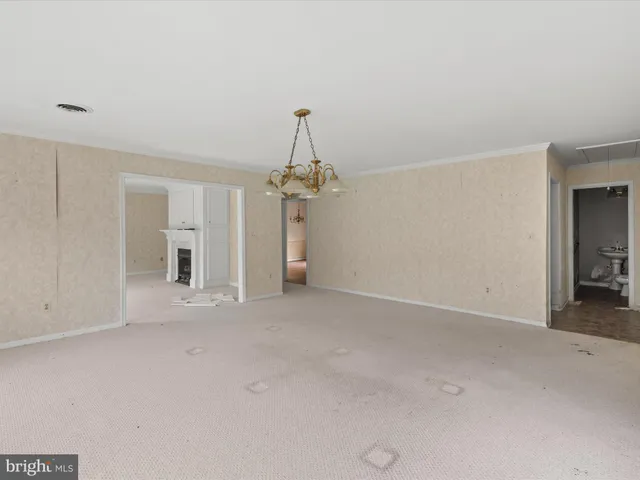 an empty room with chandelier fan and windows