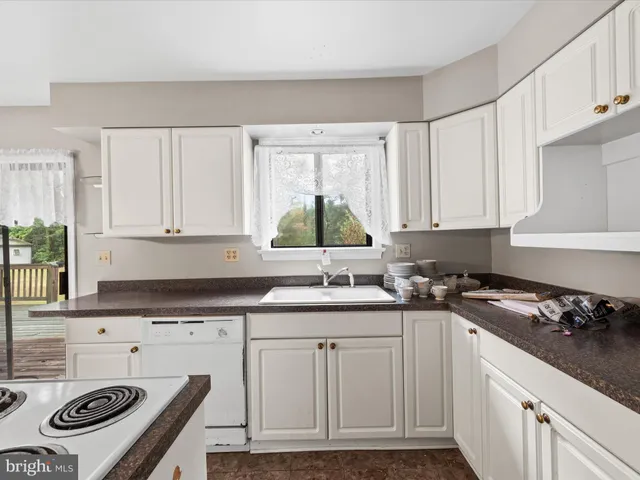 a kitchen with granite countertop a sink a stove and cabinets