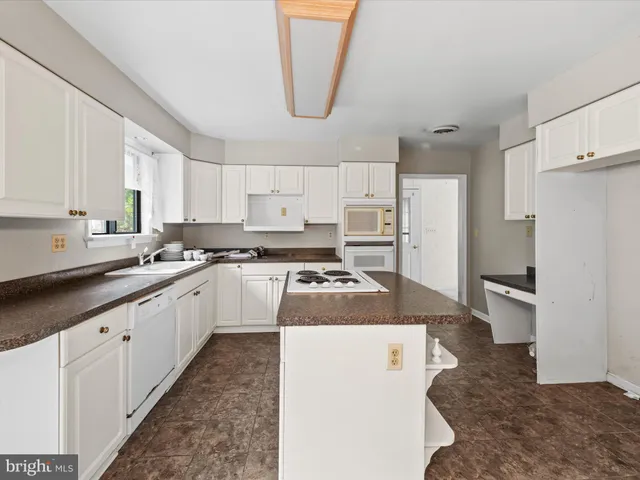 a kitchen with stainless steel appliances granite countertop a sink a refrigerator a stove a microwave and white cabinets