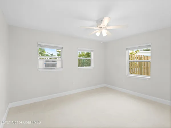 an empty room with windows and fan