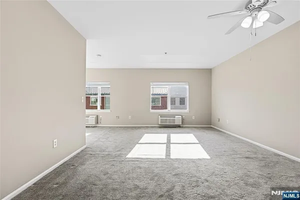 an empty room with windows and ceiling fan