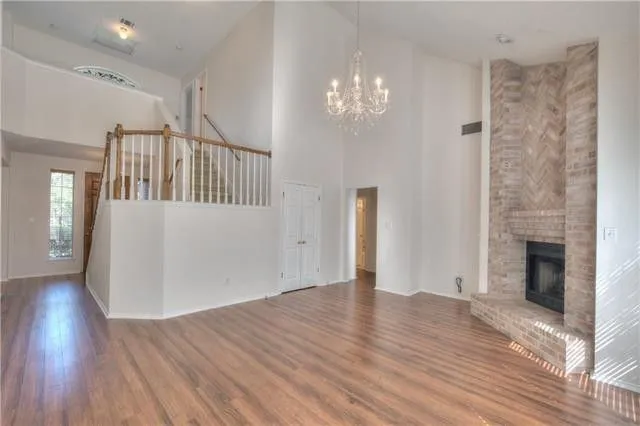 a view of an empty room with wooden floor and a fireplace