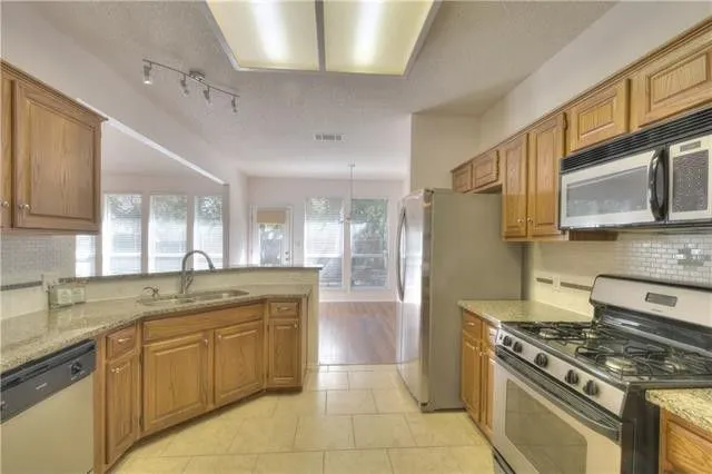 a kitchen with stainless steel appliances granite countertop a stove a sink dishwasher and a refrigerator