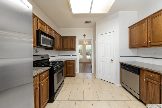 a kitchen with stainless steel appliances granite countertop a stove a sink and a microwave
