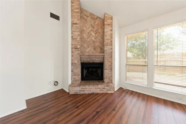 a view of a livingroom with wooden floor and a fireplace