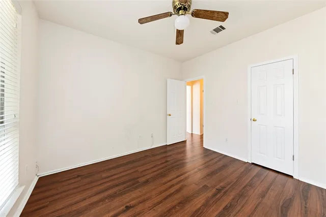 an empty room with wooden floor a ceiling fan and a window