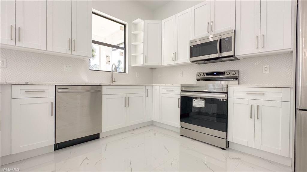 1028 19th Street Southwest Naples, FL 34117 - Photo 12 of 50 a kitchen with white cabinets stainless steel appliances and sink