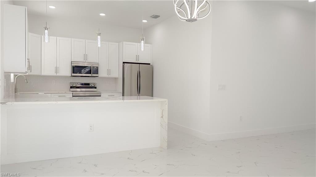 1028 19th Street Southwest Naples, FL 34117 - Photo 13 of 50 a kitchen with kitchen island a white counter top and stainless steel appliances