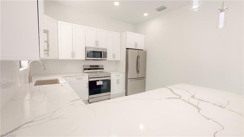 1028 19th Street Southwest Naples, FL 34117 - Photo 8 of 50 a kitchen with kitchen island a white cabinets and stainless steel appliances