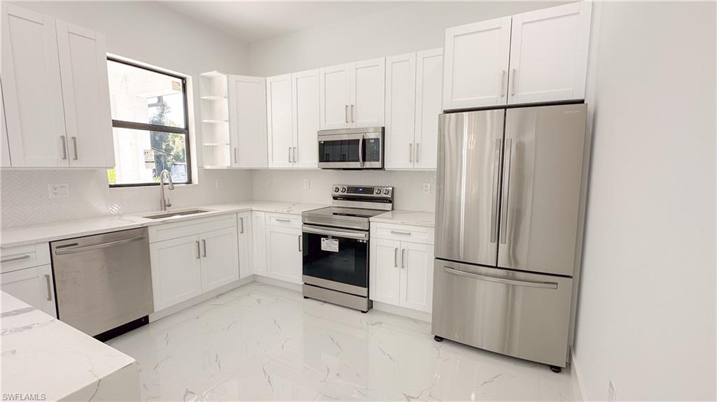 1028 19th Street Southwest Naples, FL 34117 - Photo 10 of 50 a kitchen with white cabinets and stainless steel appliances