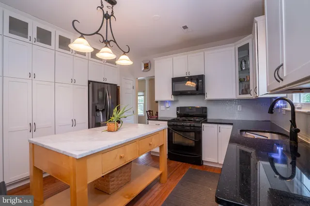 a kitchen with a refrigerator a stove a sink and white cabinets with wooden floor