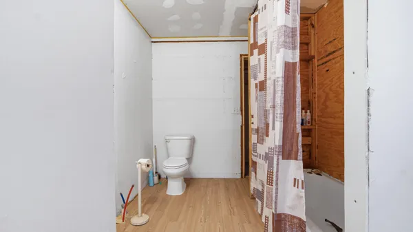 a view of a hallway with wooden floor and a bathroom
