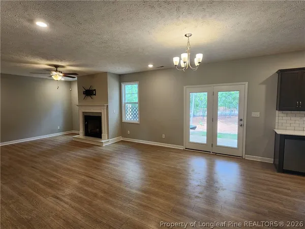 an empty room with wooden floor fireplace and windows