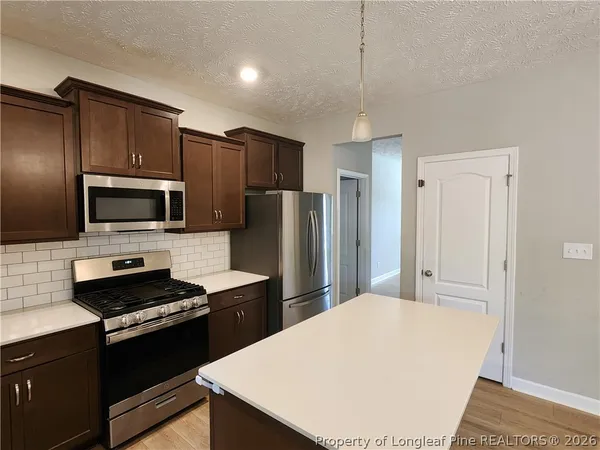 a kitchen with a refrigerator a microwave a sink and cabinets