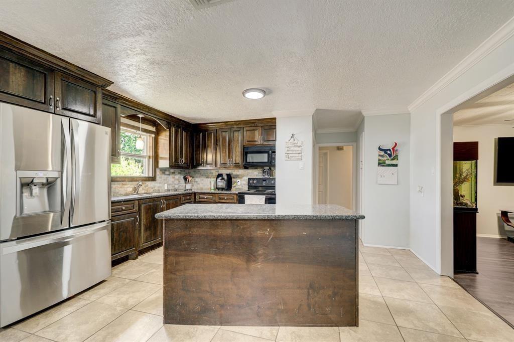 a large kitchen with granite countertop a refrigerator and a stove top oven