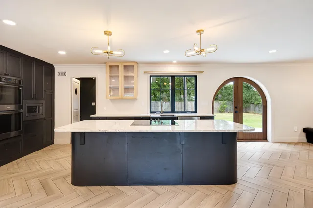 a large kitchen with stainless steel appliances a large counter top a stove a refrigerator and a sink