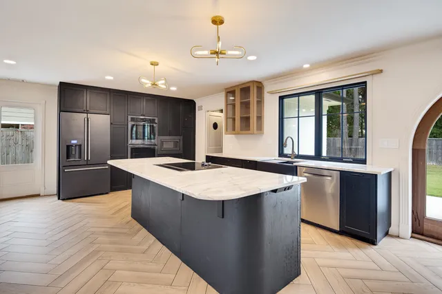 a large kitchen with kitchen island a large counter top and stainless steel appliances