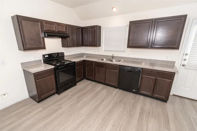 a kitchen with stainless steel appliances granite countertop wooden cabinets a stove top oven a sink and dishwasher